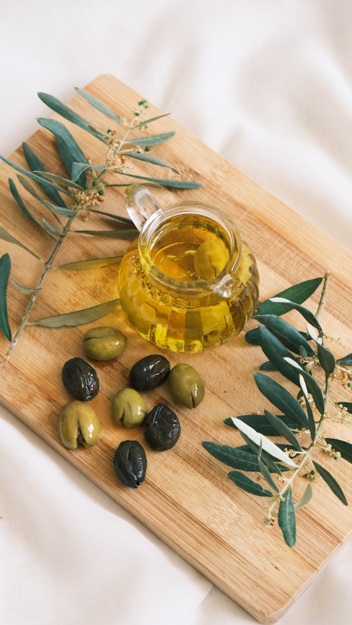 Cozy setup featuring olives and olive oil on a wooden board with olive branches.